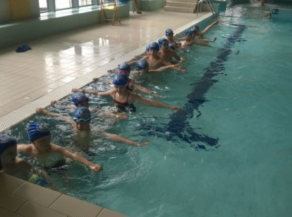dzieci w basenie uczą się pływać