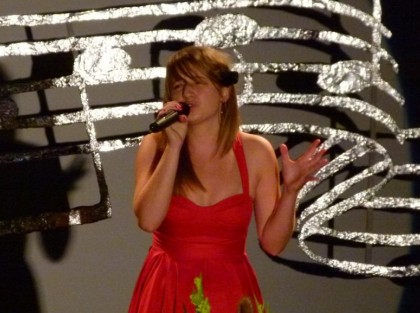 młoda kobieta w czerwonej sukience śpiewa na scenie centrum kultury