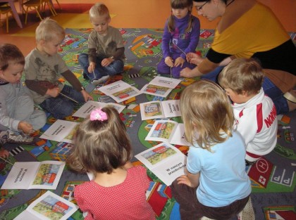 dzieci siedzące na dywanie i oglądające ilustracje