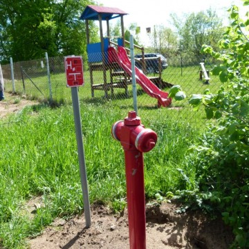 nowy hydrant na trawniku obok placu zabaw  