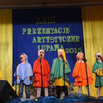 występ na scenie małych dzieci przebranych w kolorowe stroje krasnoludków
