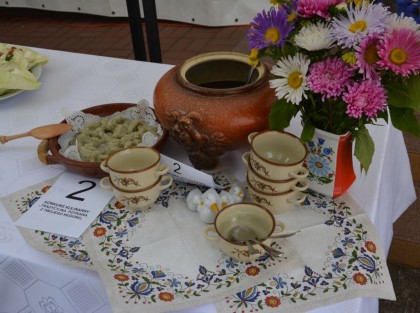 zupa w glinianym garnku a obok rondelki i potrawa z kapusty